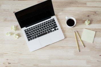 Laptop and a coffee on a wooden desk.